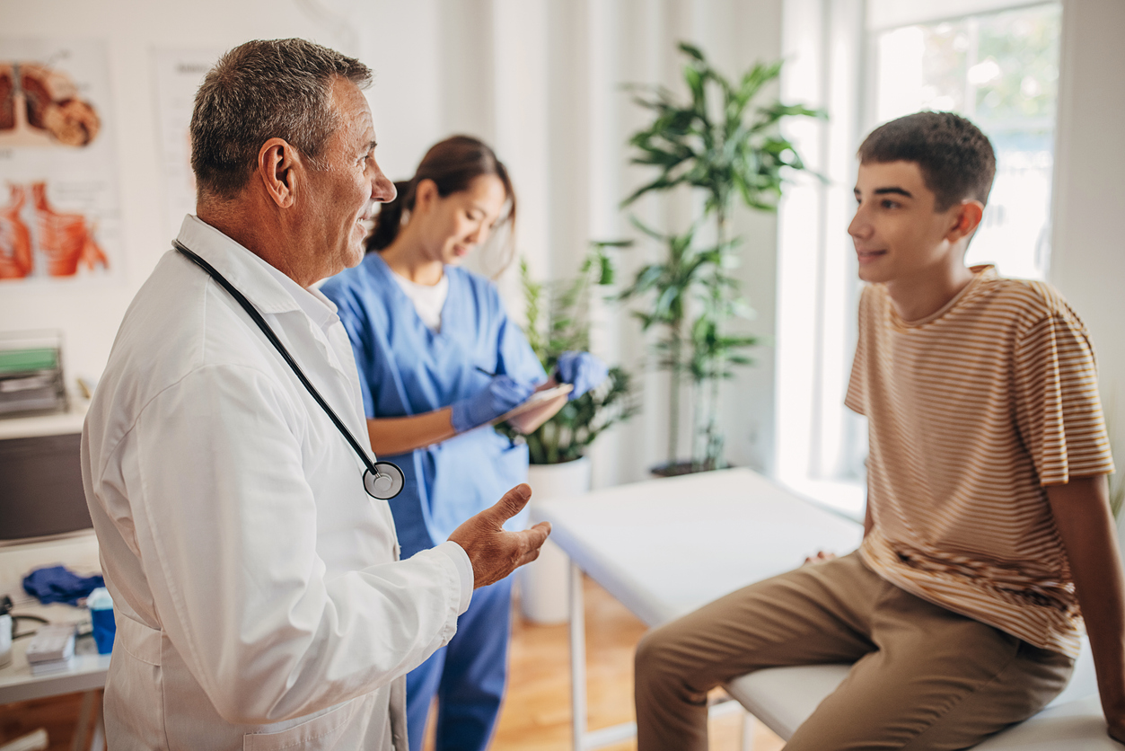 Doctor is talking and examining the patient at the clinic while nurse is taking notes in medical chart